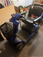 Front-left angle view showing blue body, seat, armrests and front basket