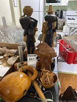 Dark wooden African carved figures of women carrying pots on heads, wooden musical instrument, and a wooden hand-held rattle. Various small carved pieces.