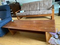 Teak coffee table in room setting with surrounding furniture showing overall item and condition