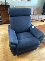 Front angled view of the blue upholstered recliner showing cushions, armrests, and overall shape