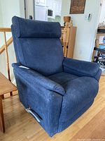 Full view of the blue upholstered recliner chair showing side and front with padded seat, backrest, and armrests, and metal recline lever.