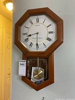 Full view of Seiko Westminster Whittingham wall clock showing octagonal wooden frame and brass pendulum visible in lower compartment.