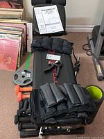 Photo showing utility bench, dumbbells, weight plate, velcro weight bands and grip strengthener on bench.