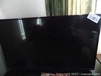 Front view of the 32-inch TV showing the black frame and screen with reflection.