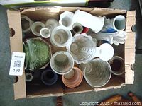 Top-down view of a large box filled with many glass and ceramic vases of varying sizes, finishes, and colors showing assortment and condition needing cleaning.