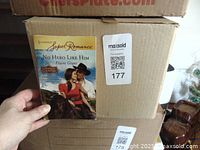 Hand holding a paperback book titled 'No Hero Like Him' by Elaine Grant, part of Harlequin Super Romance series.