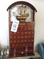 Front view of wooden perpetual calendar showing ship model, map background and date blocks