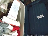 Image showing a large blue plastic storage tote filled with various Christmas decorations, including some Santa hats and other items