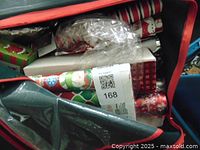 Photo showing multiple rolls of Christmas-themed wrapping paper inside a container, including snowman and candy cane designs.