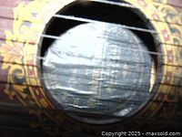Close up photo of sound hole showing decorative gold floral artwork and strings on the wooden zither body.