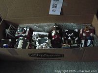 Box containing eight hand painted Christmas village buildings and accessories packed for sale.
