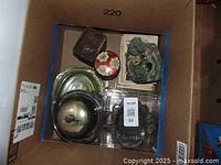 Top view of the box showing the silver butter dish, green depression glass tray, various trinket boxes, and battery-operated water fountain.