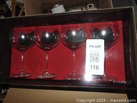 Four stemmed clear glass wine glasses in original boxed packaging with red interior and Peoples Jeweler's branding.