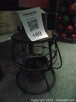 Side view of vintage propane lantern showing metal cage and top cover with handle.