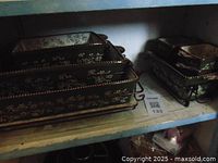 Brown Temptations casserole dishes and bread pan with floral decorations stacked on bronze metal racks.