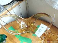 Side and top view of the amber glass decorative bowl showing its flowing curved edges and smooth glossy surface.