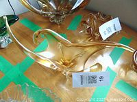 Amber-colored glass fruit or candy dish with flowing organic shape, viewed from above on wooden surface.