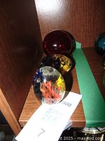 Three vintage glass paperweights displayed together showing size and color variety