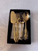 Photo of the 4 piece gold plated hostess set inside the black Royal Sealy box showing the serving fork, serving spoon, ladle, and pie server.