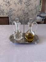 Crystal oil and vinegar cruet set on metal tray, showing one cruet with clear liquid and one with golden liquid