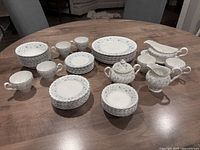 Full set including plates, bowls, mugs, gravy boat, milk jug, sugar bowl arranged on a wooden table.