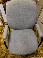 Front view of gray fabric office chair showing backrest, seat, and padded armrests with black metal frame.