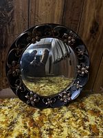 Full view of the vintage round convex mirror showing the floral brass floral metal frame and reflection.