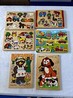 Six wooden peg puzzles showing themes of farm animals, vehicles, and characters including a bear and dogs.