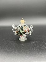 Front view of the antique hand-painted glass snuff bottle showing dark multicolor landscape painting, clear glass handles, and removable stopper.