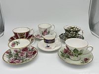 Six different patterned English bone china teacups and matching saucers arranged in two rows displaying floral designs and gold detail
