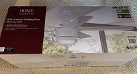 Photo of the product box showing 52-inch indoor ceiling fan from Home Decorators Collection with LED light and matte white finish.