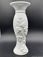 Front view of white ceramic jardinière vase showing detailed grapevine motif relief decoration.