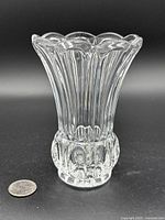 Clear glass vase with scalloped rim and vertical cut design, shown with quarter for scale
