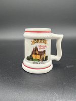 Front side of ceramic shot glass with image of Bran Dracula's Castle Romania, red decorative stripes top and bottom.