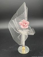 Full view of the Pink Crystal Porcelain figurine with mesh fabric wrapped around stem and rose attached on top of crystal base.