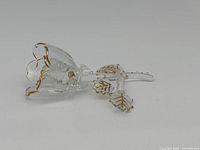 Side view of a clear glass rose with gold detailing on the petals and leaves.