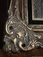 Close up of ornate gold gilded corner of picture frame showing detailed floral and scroll relief decoration with some patina.