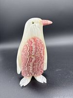 Front view of alabaster penguin figurine showing ivory body with pink wings and beak, white feet, polished smooth surface