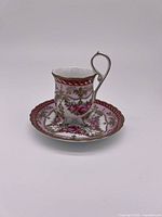 Side view of vintage porcelain footed teacup and matching saucer with floral patterns and gold accents.