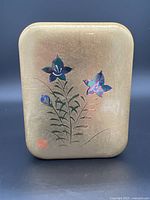 Top view of rectangular gold decorative box with floral design and minor wear.