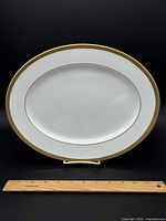 Full view of the 12-inch oval Lenox Landmark Gold serving platter with wooden ruler for size reference.