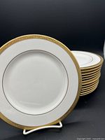 Stack of 14 white porcelain Lenox Landmark Gold 8-inch salad plates with wide gold rim and embossed vine pattern.