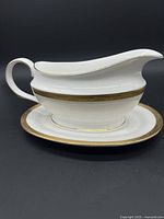Gravy boat positioned on top of the matching underplate showing gold trim detail and graceful handle.