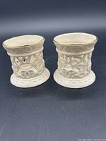 Side view of the two white Lenox ceramic votive holders showing detailed cutout designs and gold rim