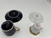 Bottom view of two demitasse cups and saucers showing brand marks of Limoges Castel and Limoges Imperia