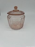 Front view of Mayfair pink depression glass cookie jar with lid closed, showing faceted sides and embossed floral design.