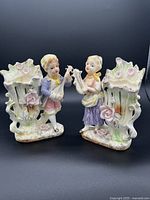 Pair of Victorian-style porcelain figurines with pastel colors and musical instruments, shown frontally.