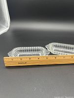 Two clear glass Art Deco style jewelry trays placed side by side with a ruler showing size approximately 5 1/2 inches long.
