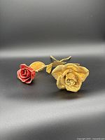 Set of two preserved roses on a black background; one red with gold dipped edges, one fully gold dipped.