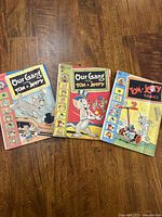 Three Tom & Jerry comics by Dell Comics arranged side by side on wooden floor showing front covers clearly